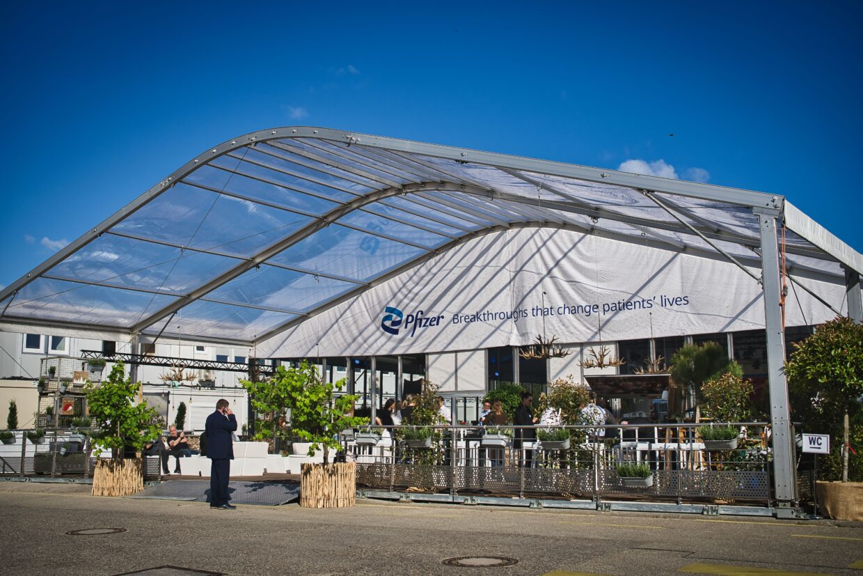 Zelt mit Glasdach, Überschrift mit Pfizer, Sitzgelegenheiten außen