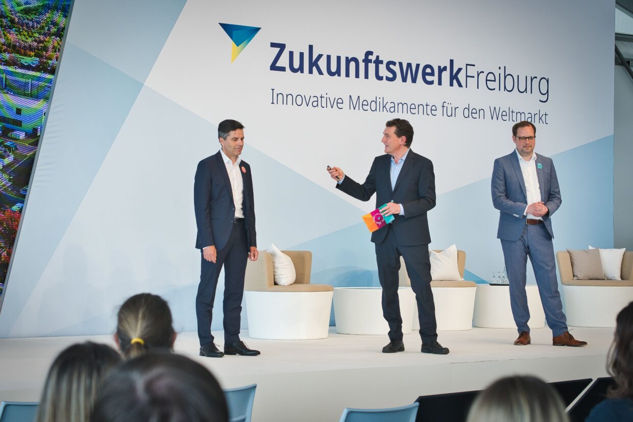 3 Männer in Anzügen halten einen Vortrag